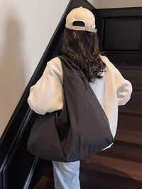 Person wearing a white hoodie, black vest, and beige cap walking up a staircase.