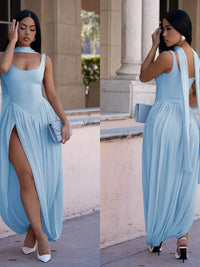 Woman in a light blue dress with a slit standing outdoors.