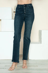 Dark blue jeans worn by a person standing indoors with a neutral background