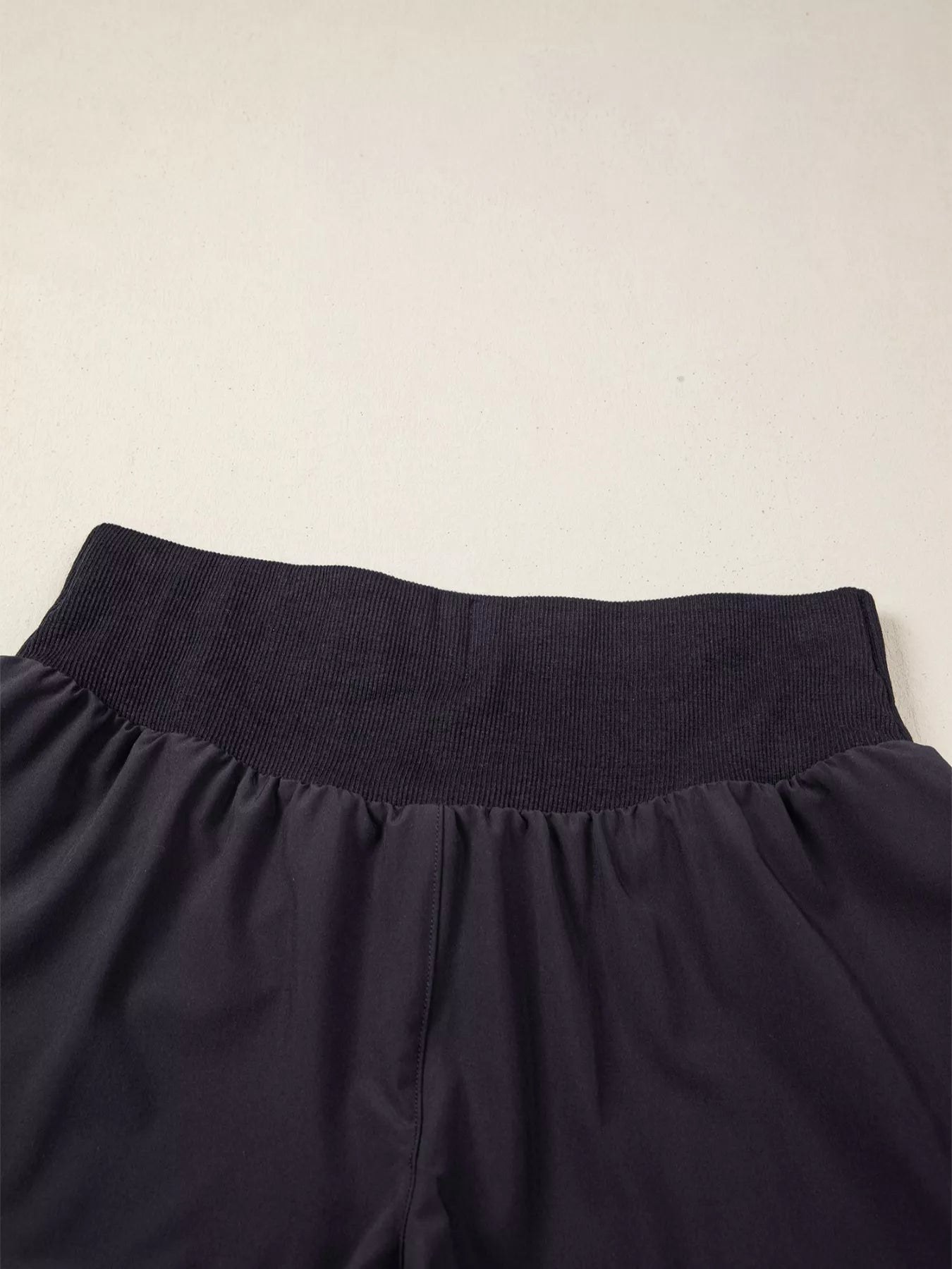 Navy blue pants with a textured waistband on a beige background