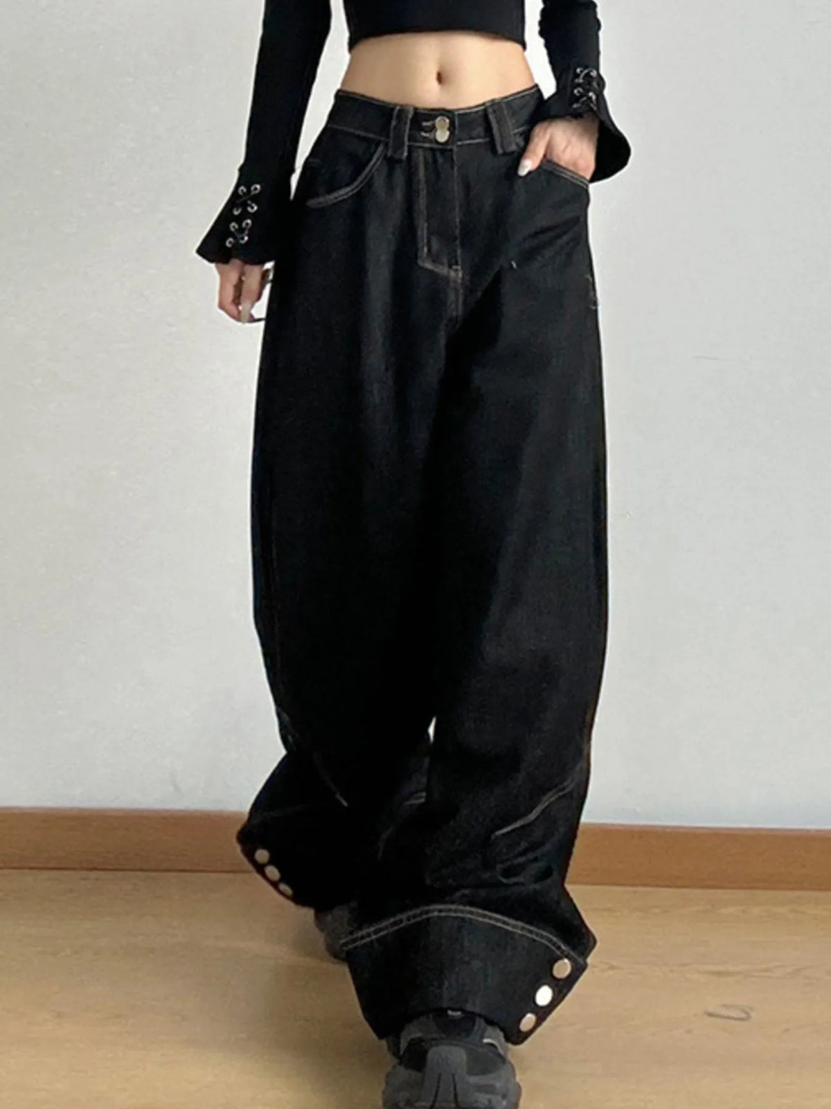 Person wearing black wide-leg jeans on a plain background