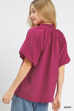 Woman wearing a berry-colored blouse with short sleeves on a white background