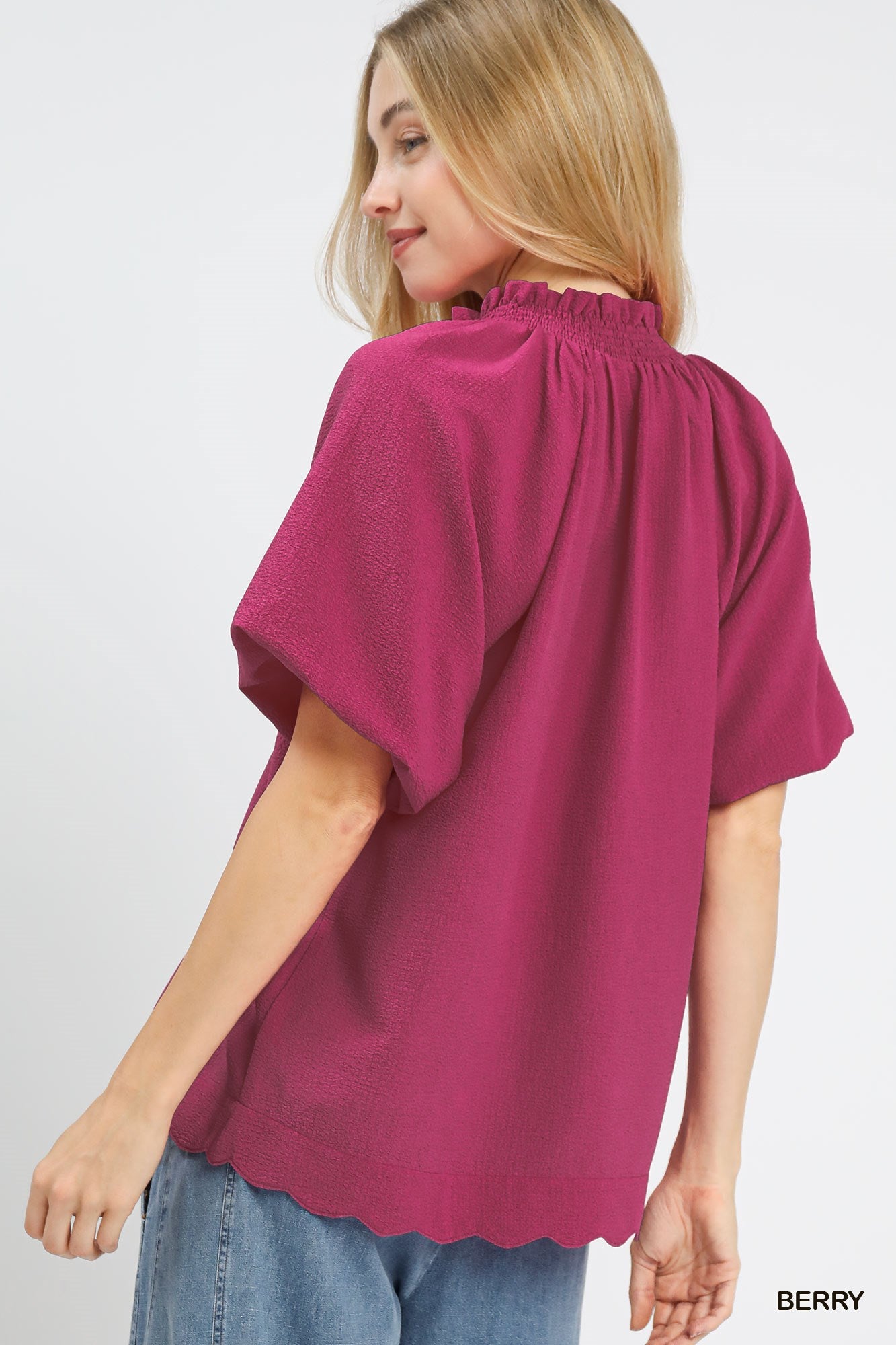 Woman wearing a berry-colored blouse with short sleeves on a white background