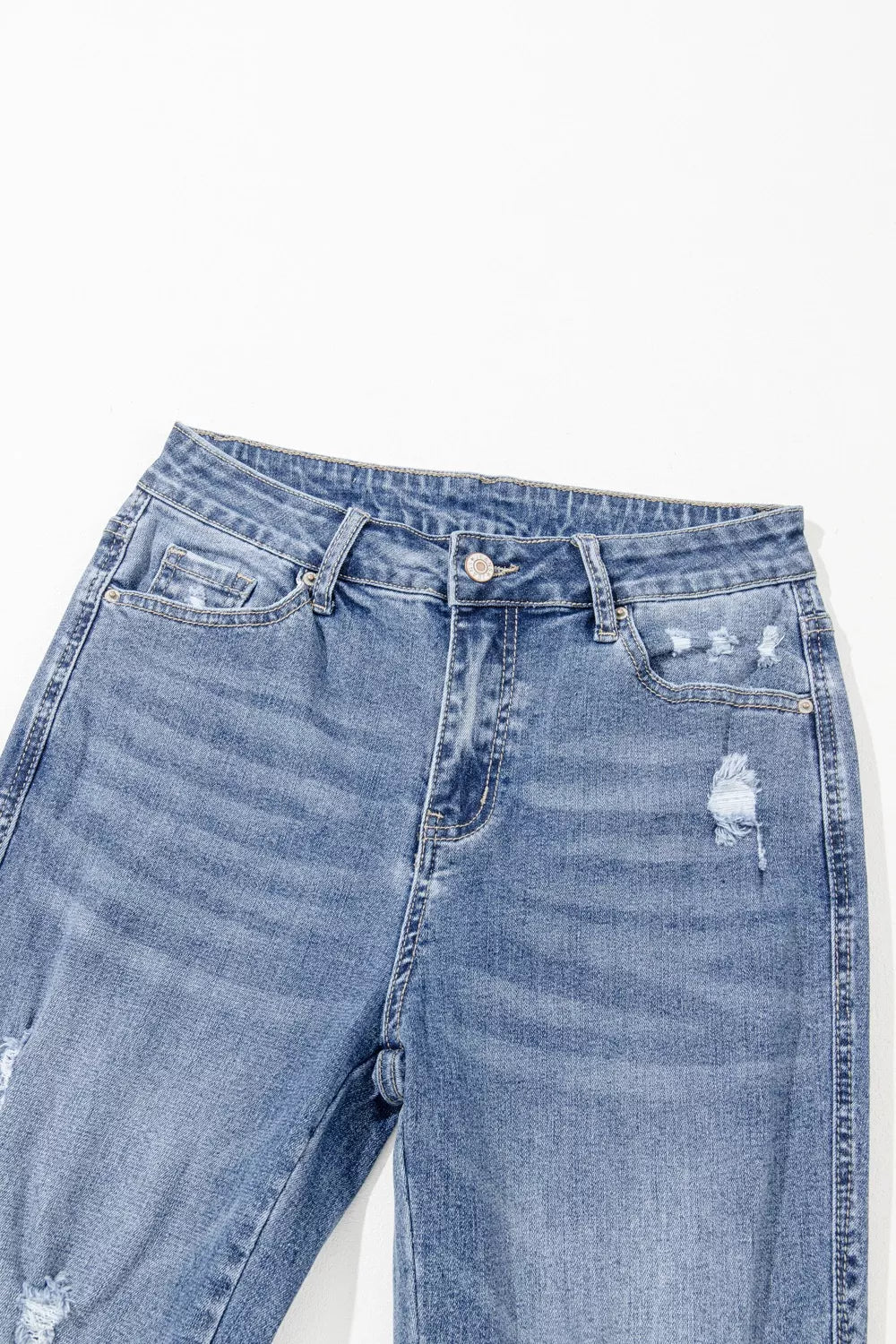 Blue jeans with slight distressing on a white background