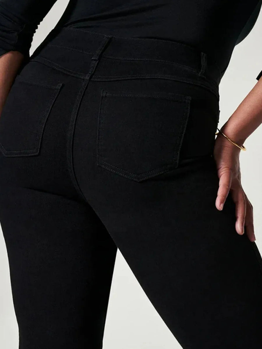 Person wearing black pants with a plain background