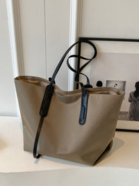 Beige tote bag with black handles on a light surface