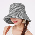 Woman wearing a black and white checkered bucket hat on a light gray background
