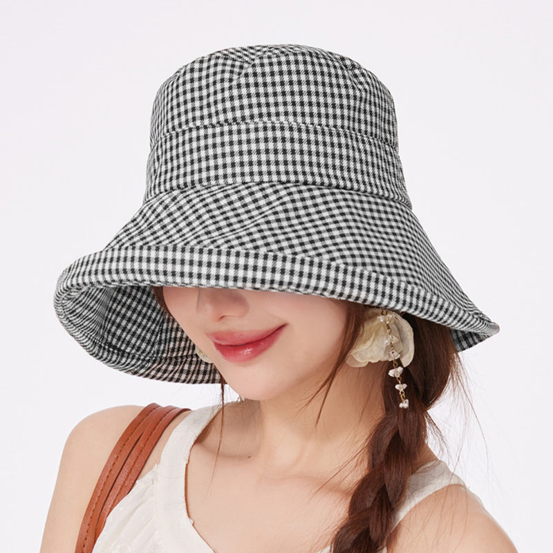 Woman wearing a black and white checkered bucket hat on a light gray background