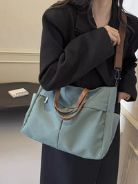 Person holding a light blue handbag with a brown strap indoors.