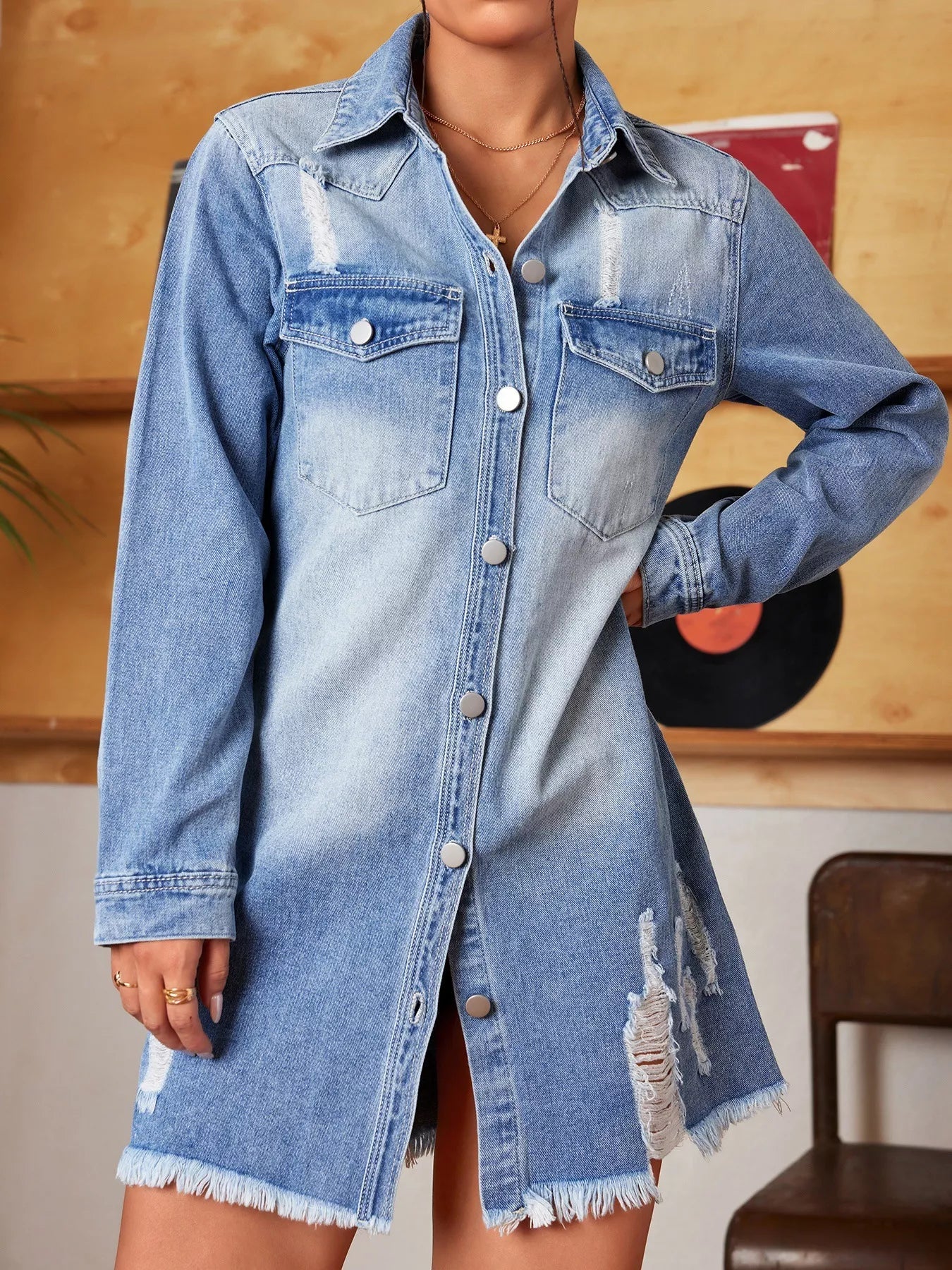 Denim shirt dress worn by a person with a wooden wall background