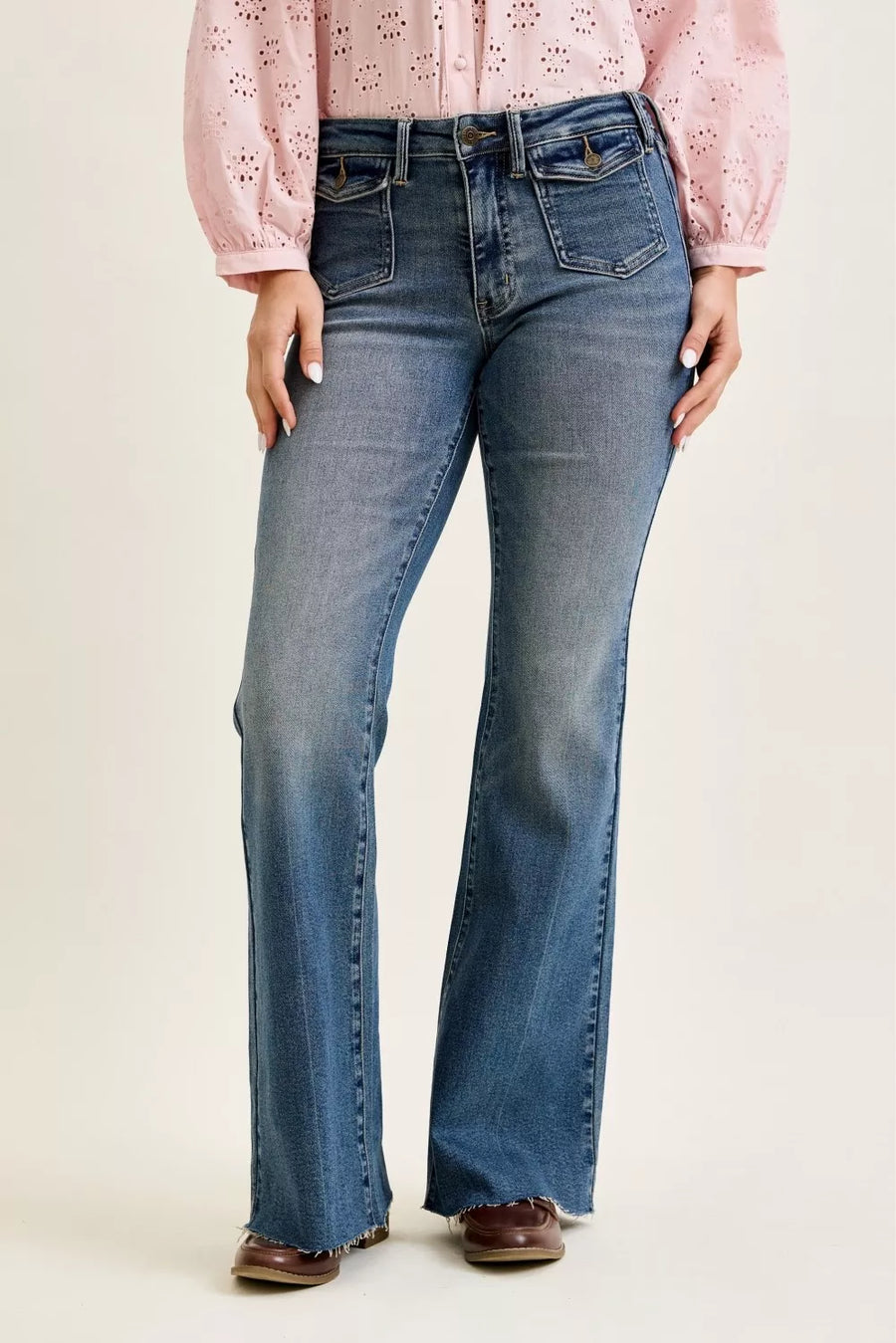 Person wearing blue jeans and a pink blouse on a plain background