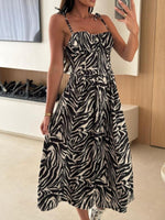 Woman wearing a zebra print dress in a room with a television and wooden cabinet.