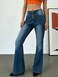 Person wearing blue flared jeans with a white wall and abstract art in the background