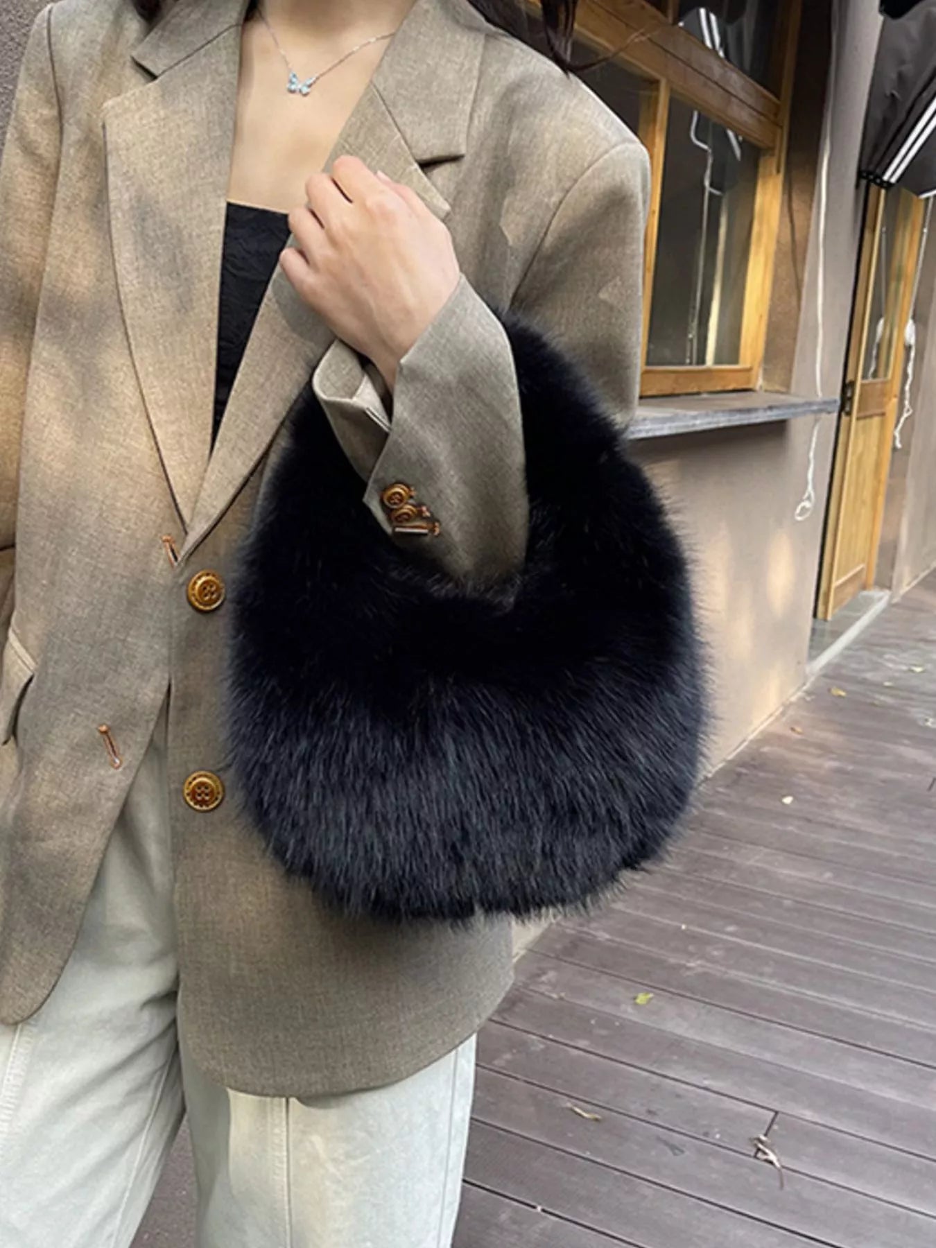 Person wearing a beige blazer with a dark fur stole outdoors.