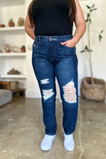 Person wearing blue distressed jeans and a black top in an indoor setting.