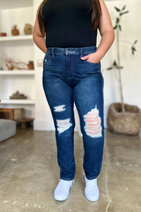 Person wearing blue distressed jeans and a black top in an indoor setting.