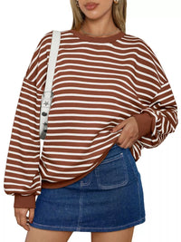 Woman wearing a brown and white striped sweater with a blue denim skirt on a white background