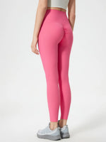 Person wearing bright pink leggings on a white background