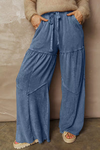 Person wearing blue wide-leg pants with a beige sweater against a neutral background