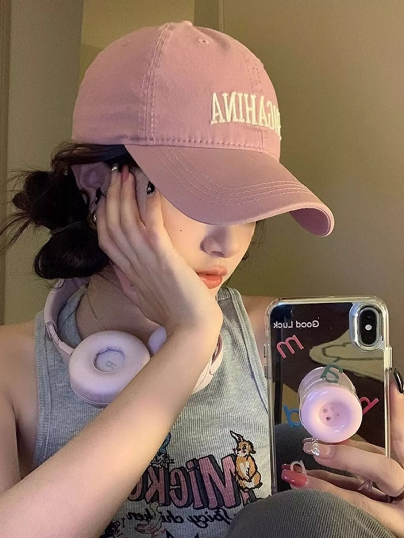 Person wearing a pink cap with 'AMIAH' branding, holding a phone with a clear case.