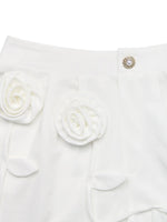 White garment with floral details and a decorative button on a white background