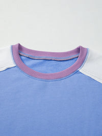 Close-up of a blue shirt with a purple collar on a light gray background