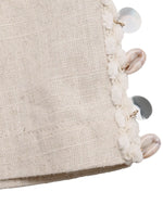 Close-up of a textured fabric surface with decorative buttons and beads on a white background