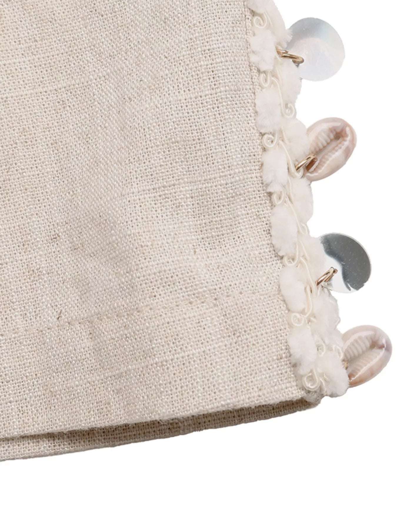 Close-up of a textured fabric surface with decorative buttons and beads on a white background