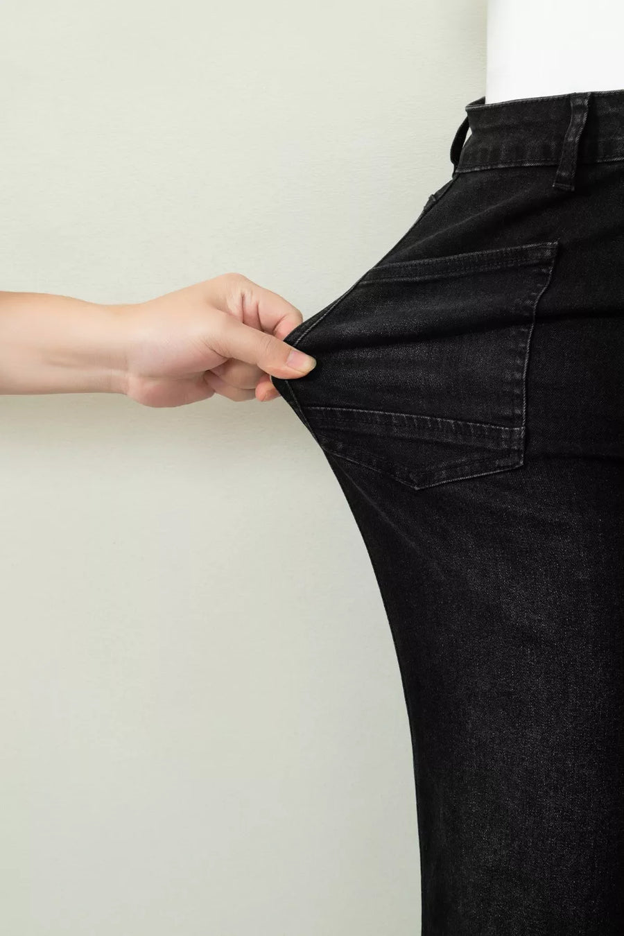Person wearing black jeans with a plain background