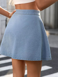 Person wearing a light blue denim skirt with a blurred background
