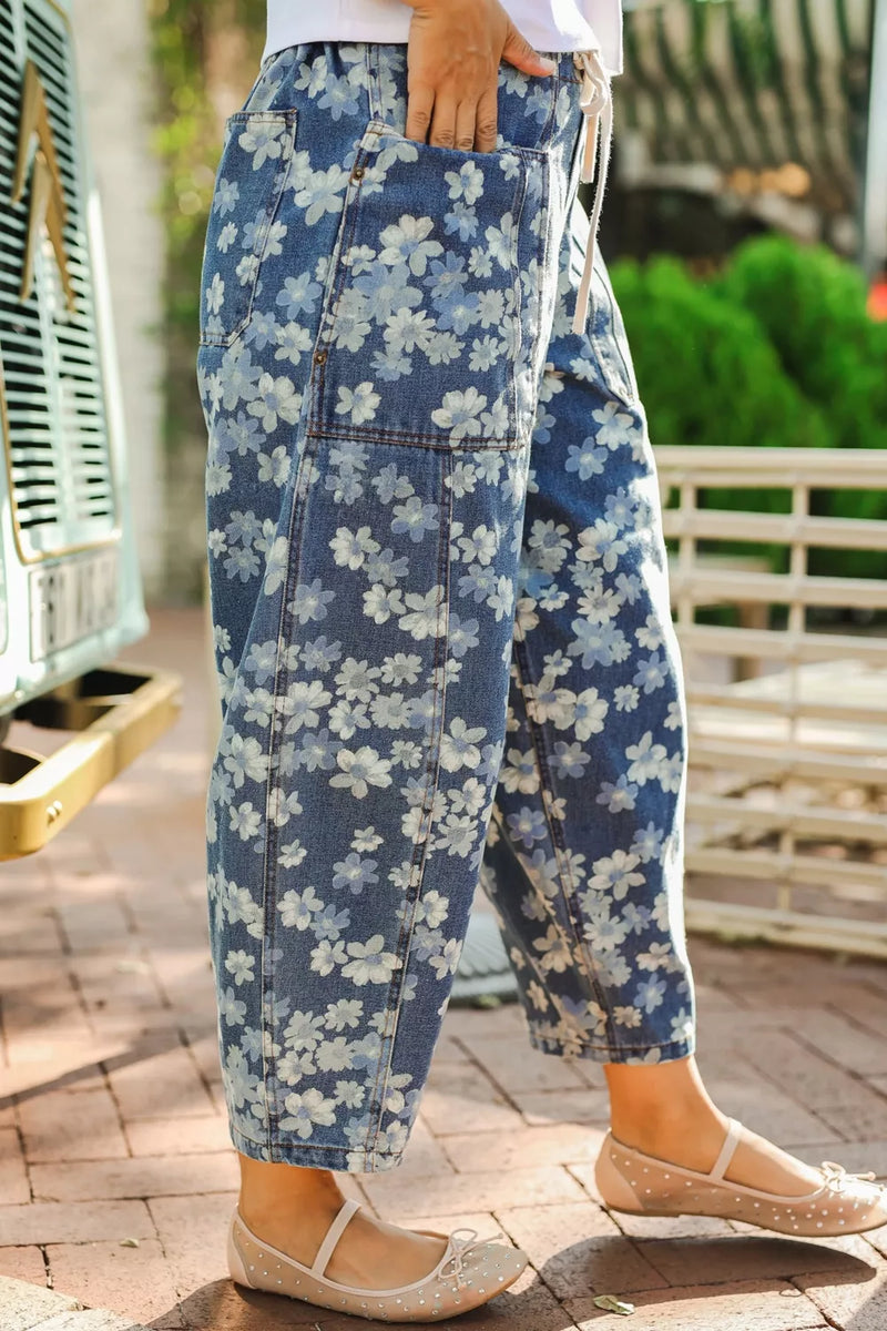 Person wearing blue floral pants with a blurred outdoor background