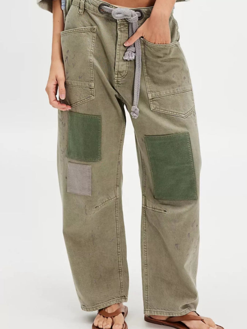 Person wearing olive green cargo pants with patchwork design on a white background