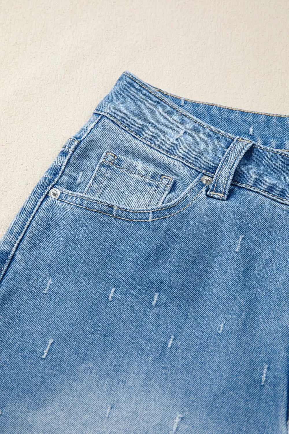 Close-up of blue denim jeans with a beige background