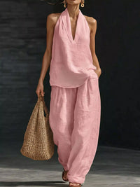 Woman wearing a pink outfit holding a woven bag against a dark background