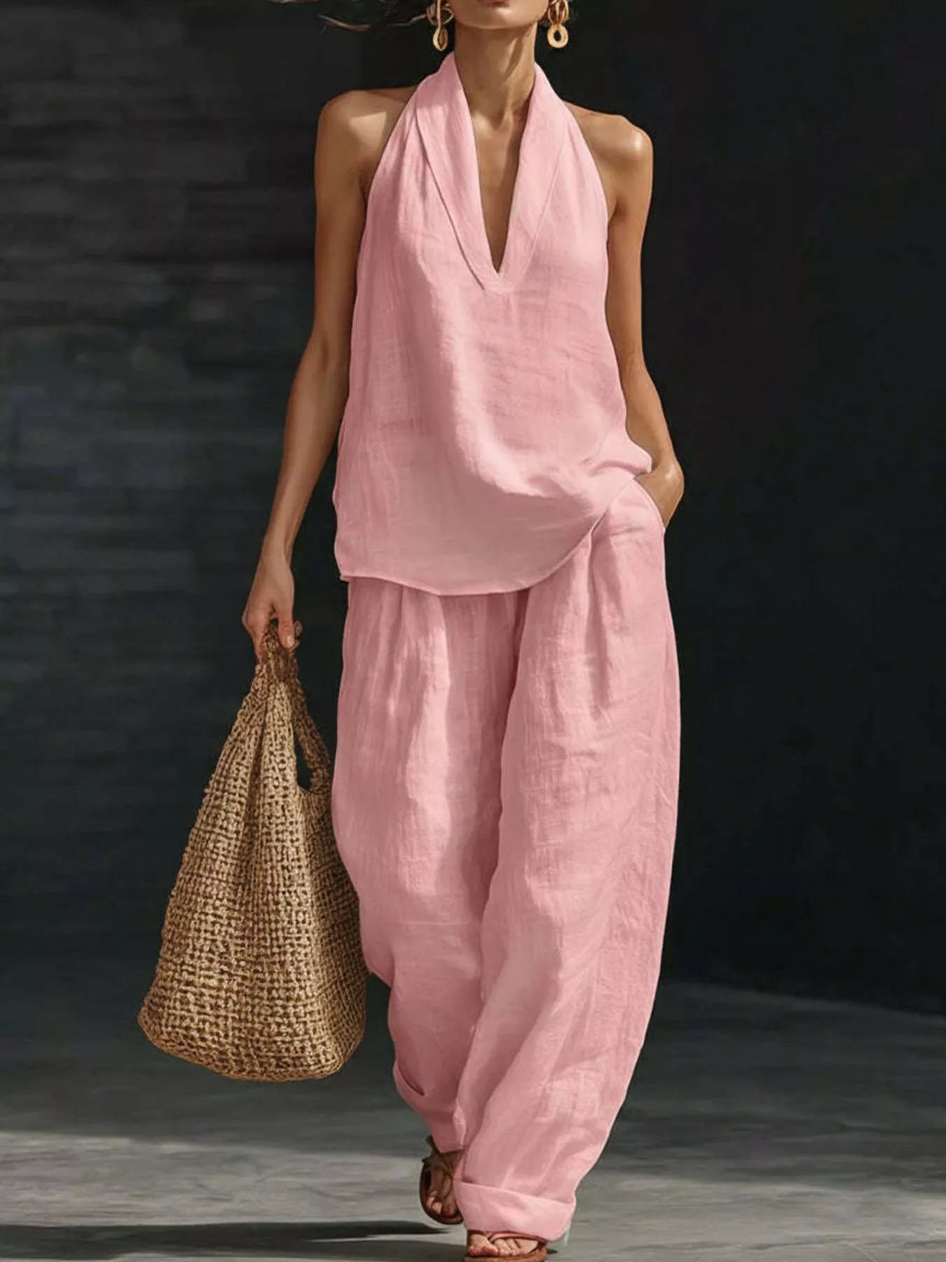 Woman wearing a pink outfit holding a woven bag against a dark background