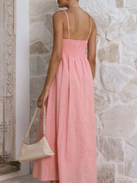 Woman wearing a pink dress against a stone wall.