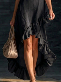 Person wearing a black dress with ruffles holding a beige handbag.