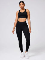 Woman wearing a black sports bra and leggings set on a white background