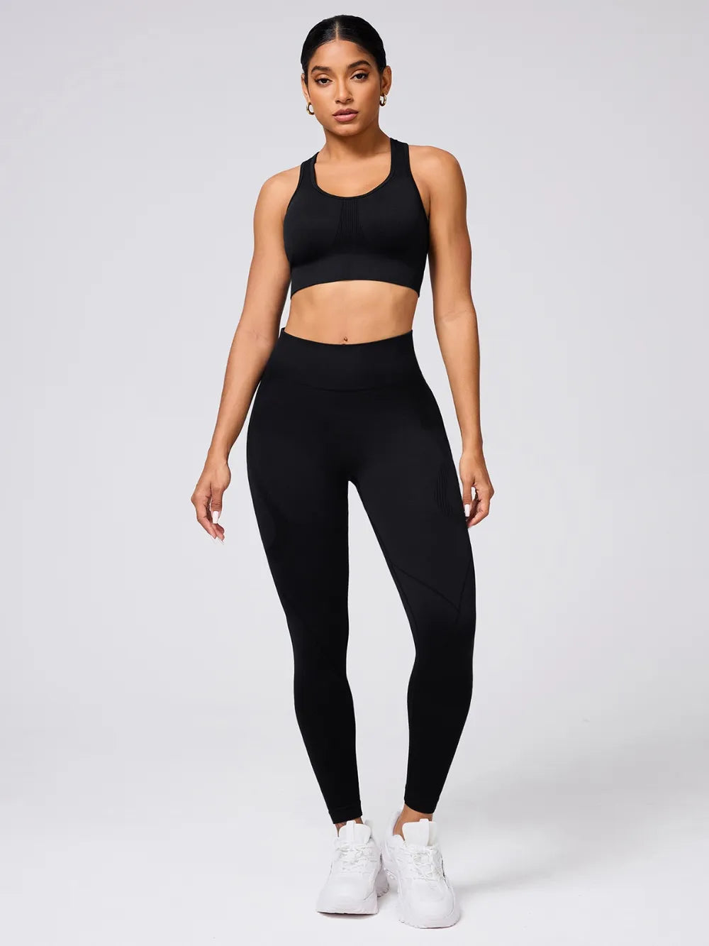 Woman wearing a black sports bra and leggings set on a white background