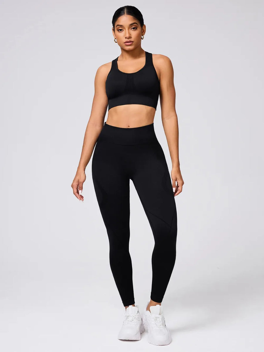 Woman wearing a black sports bra and leggings set on a white background