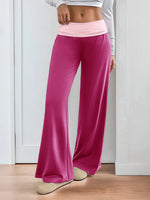 Person wearing pink wide-leg pants and a light gray top against a white wall.