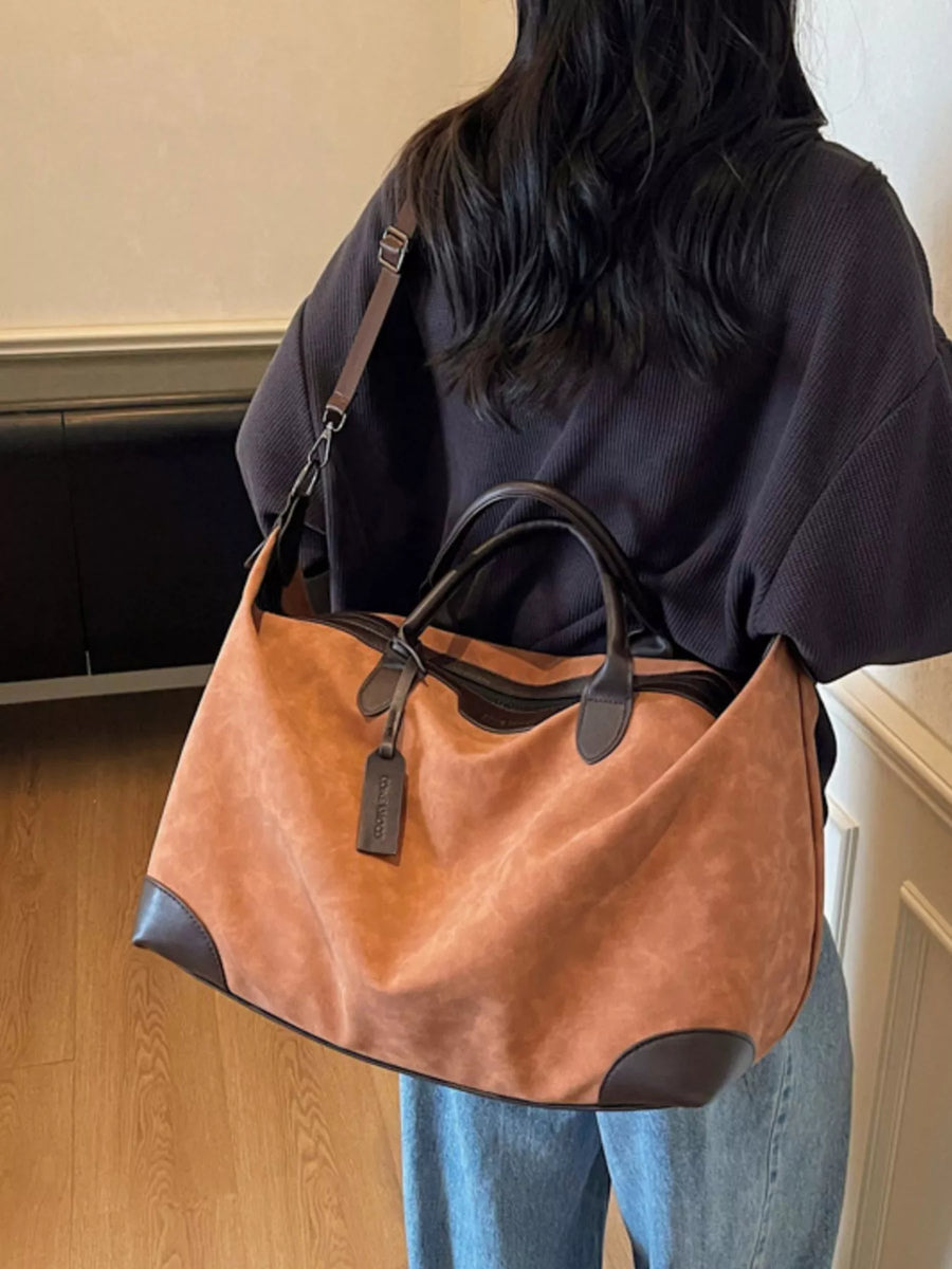 Person holding a brown leather handbag indoors