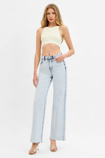 Woman wearing a light-colored top and light blue jeans on a white background