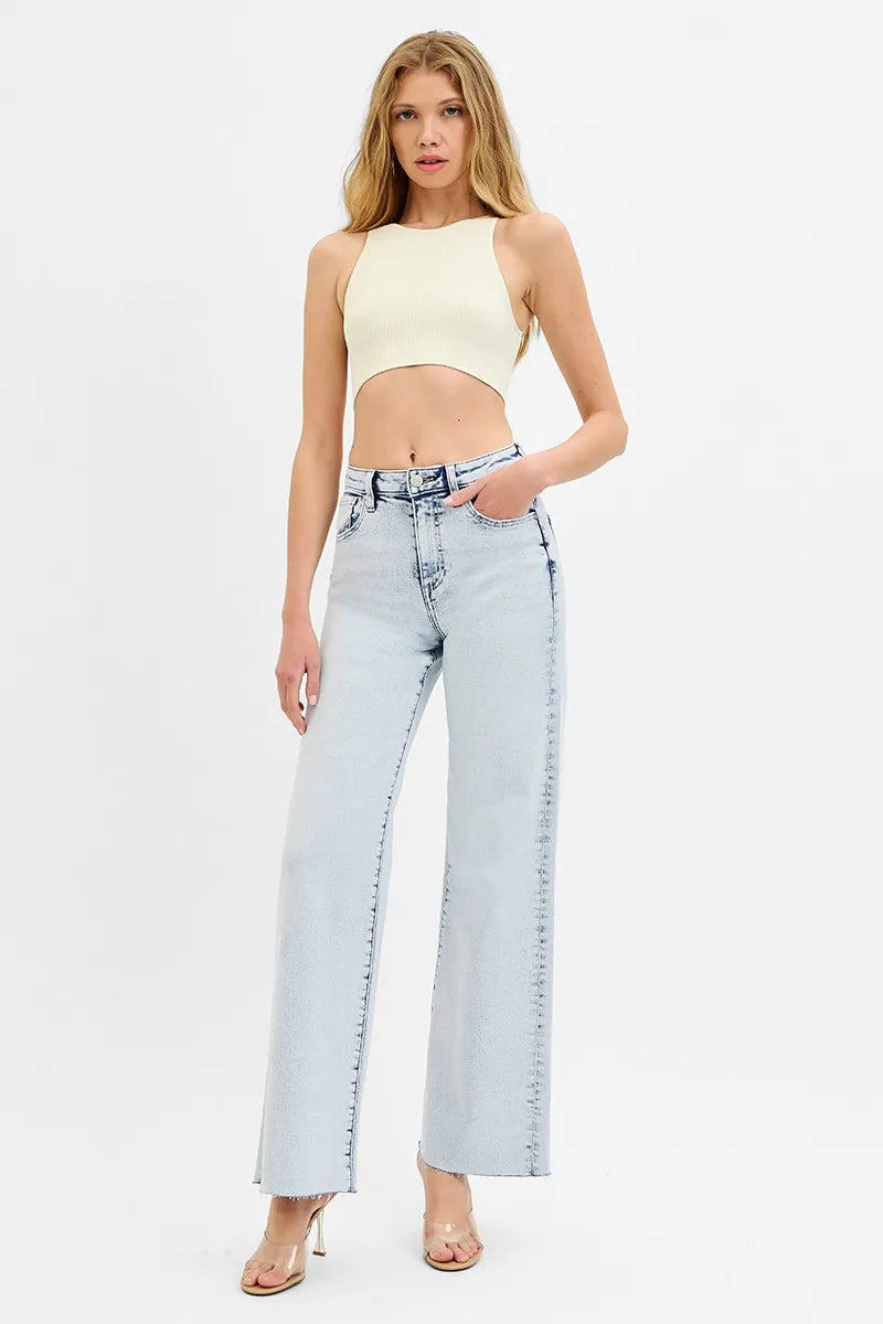 Woman wearing a light-colored top and light blue jeans on a white background