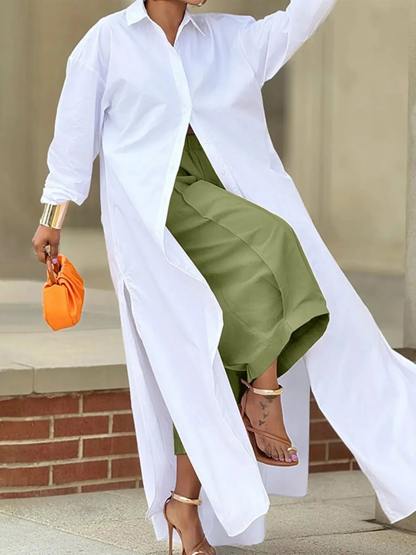 Person wearing a white shirt and green skirt with an orange clutch.