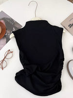 Black sleeveless top on a hanger with books and glasses on a white surface