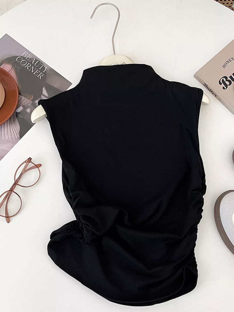 Black sleeveless top on a hanger with books and glasses on a white surface