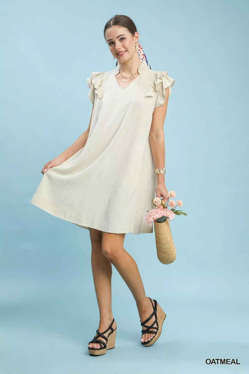 Woman wearing a white dress with ruffled sleeves against a light blue background
