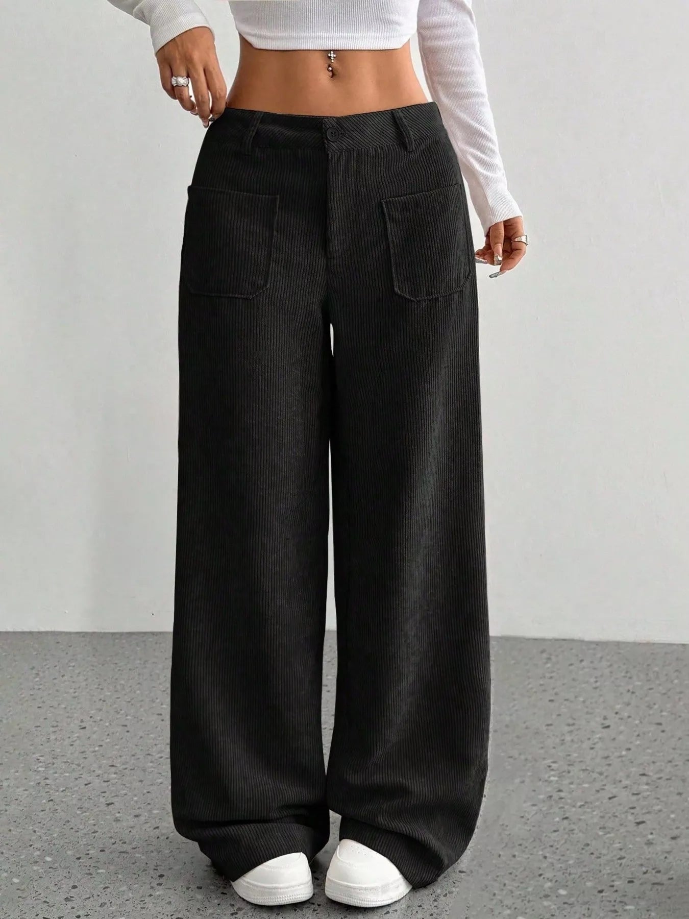 Person wearing black wide-leg pants and white shoes on a plain background
