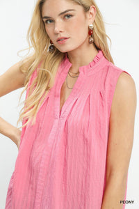Woman wearing a pink sleeveless top with a plain background